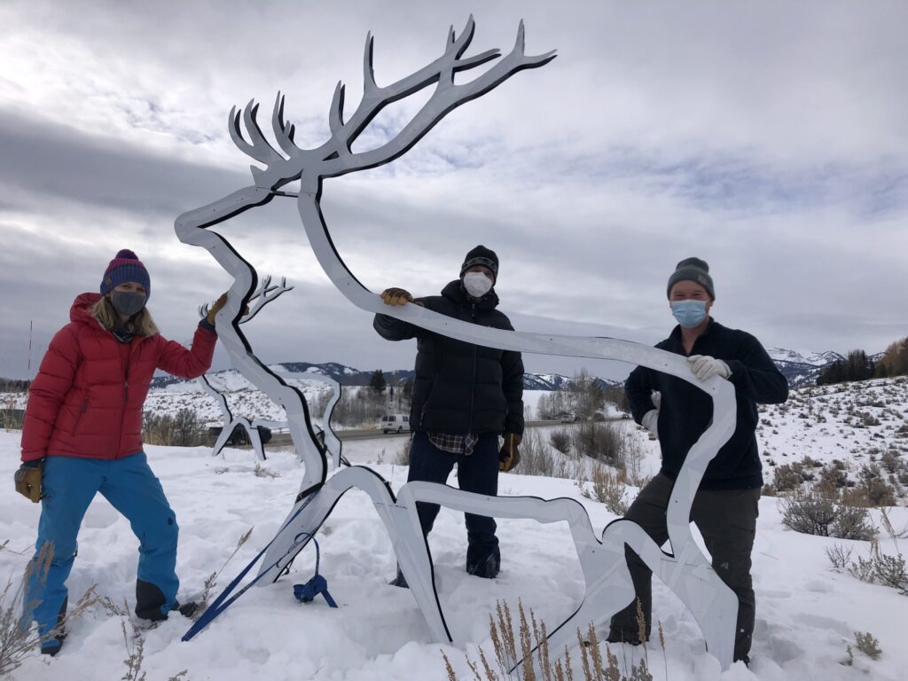 Bari Bucholz, Bland Hoke, and Chris Colligan stand next to one of the elk silhouettes they helped students install.