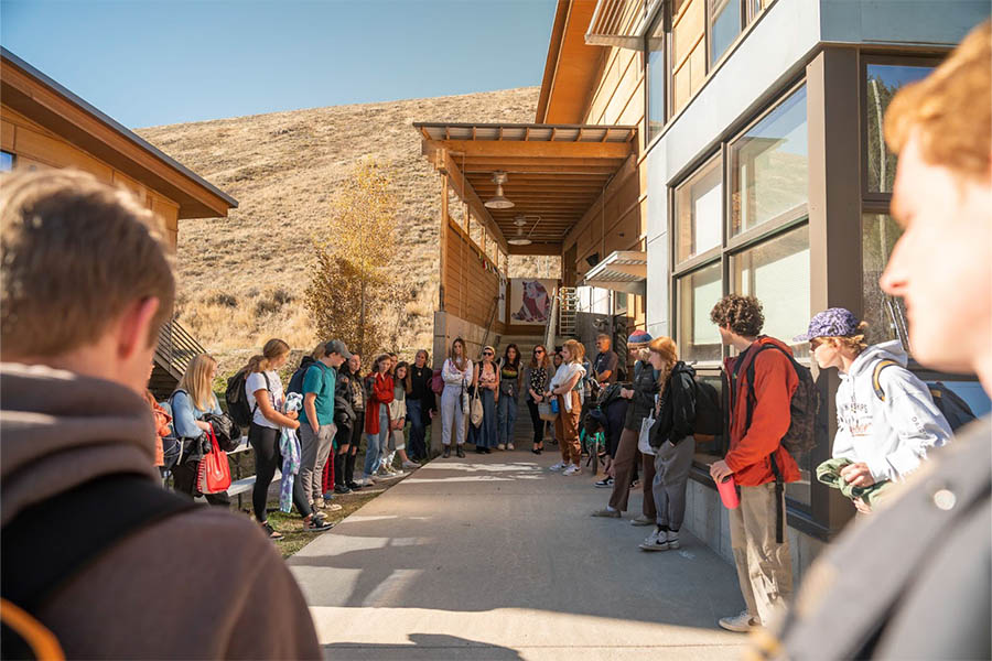 A group of Mountain Academy students and faculty participating in a Closing Circle meeting outside the Jackson Campus building.